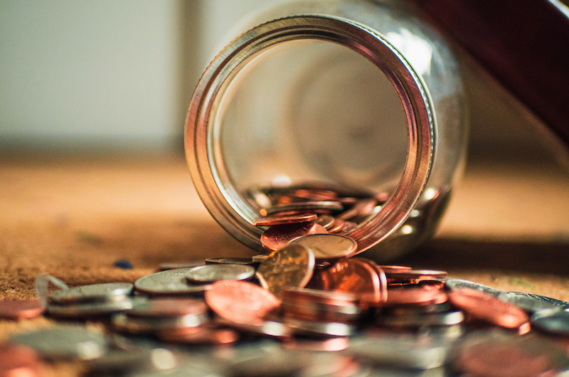 Münzen, die aus einem liegenden Glas fallen